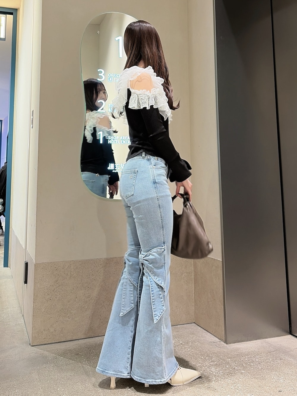 ブラック系のTシャツ/カットソー、ブルー系のデニムパンツ、ブラウン系のハンドバッグを着用したレディースの冬コーディネートの4枚目の写真