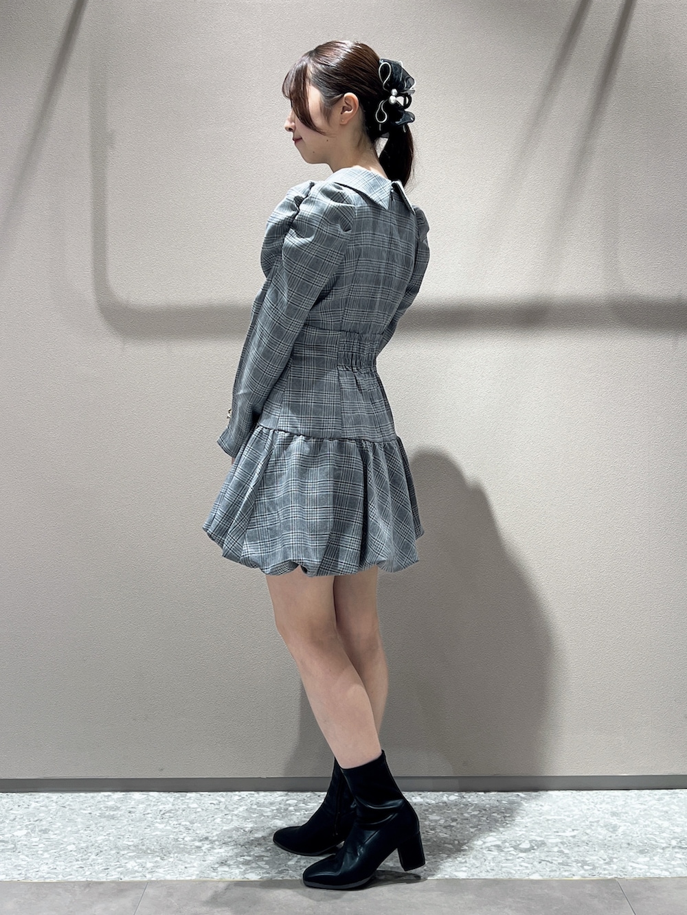 グレー系のワンピース、ブラック系のブーツを着用したレディースの秋コーディネートの2枚目の写真