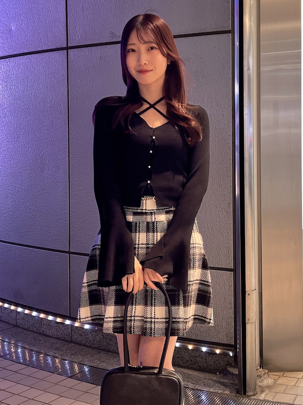 ブラック系のスカート、ブラック系のニット/セーター、ブラウン系のローファーを着用したレディースの冬コーディネートの5枚目の写真