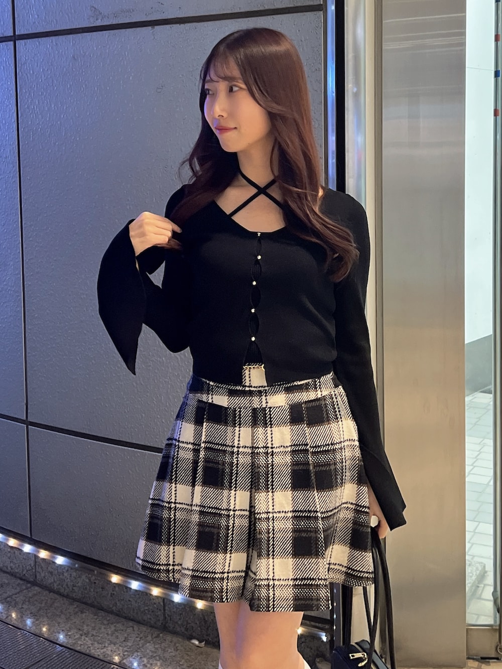 ブラック系のスカート、ブラック系のニット/セーター、ブラウン系のローファーを着用したレディースの冬コーディネートの6枚目の写真