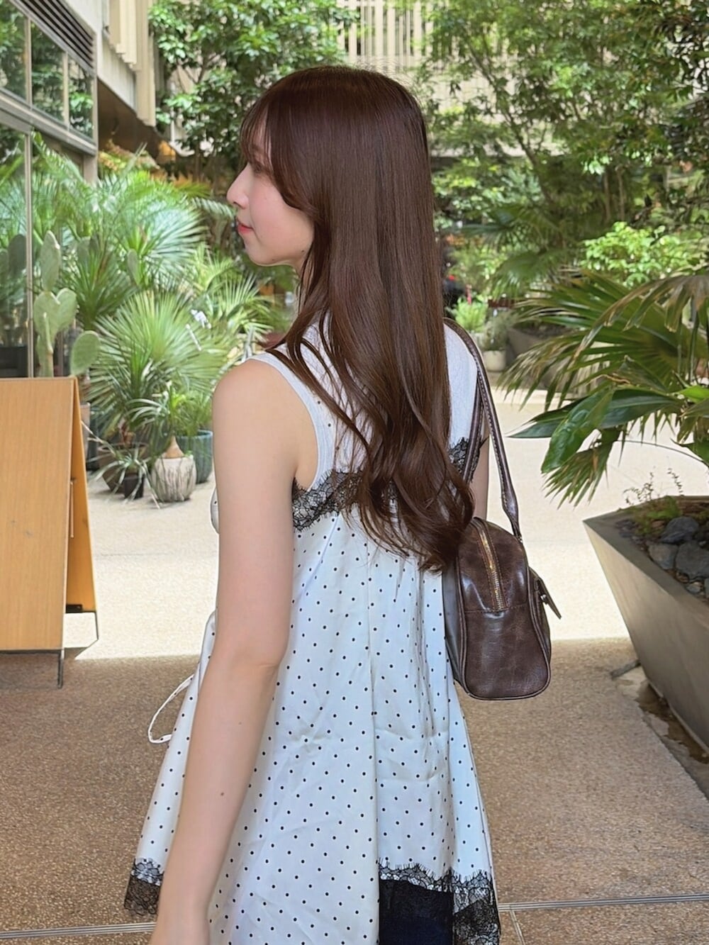 ブルー系のデニムパンツ、ブラック系のパンプス、ホワイト系のキャミソールを着用したレディースの夏コーディネートの8枚目の写真