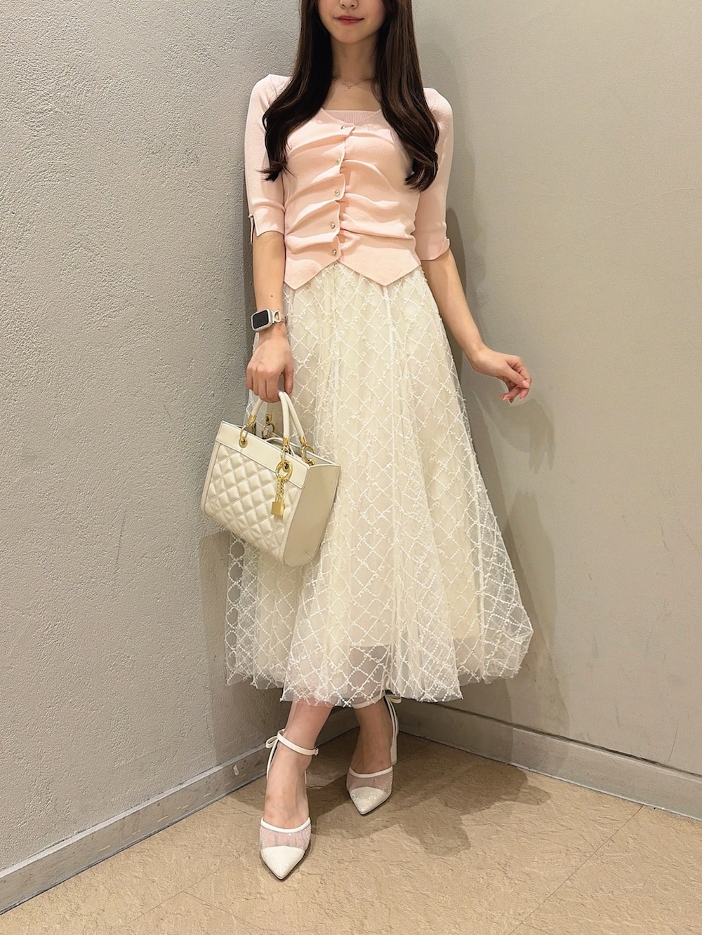 ホワイト系のパンプス、ホワイト系のハンドバッグ、ホワイト系のスカートを着用したレディースの夏コーディネートの2枚目の写真
