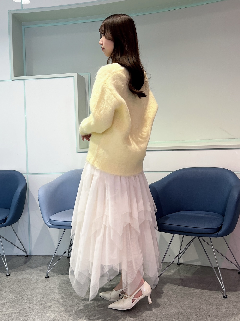 イエロー系のカーディガン/ボレロ、ホワイト系のスカート、ホワイト系のパンプスを着用したレディースの冬コーディネートの3枚目の写真