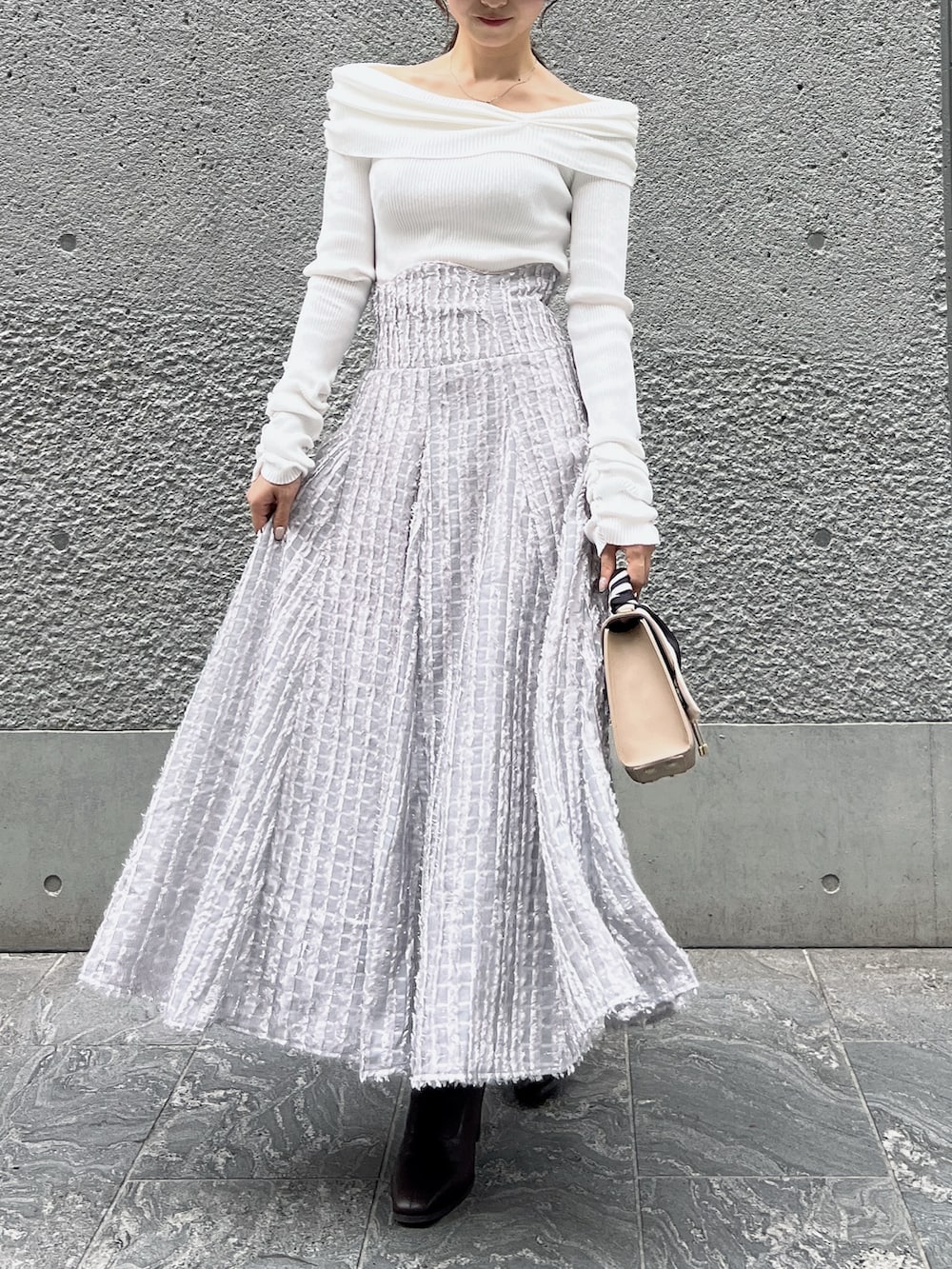 グレー系のスカート、ホワイト系のニット/セーター、ベージュ系のショルダーバッグを着用したレディースの秋コーディネートの2枚目の写真