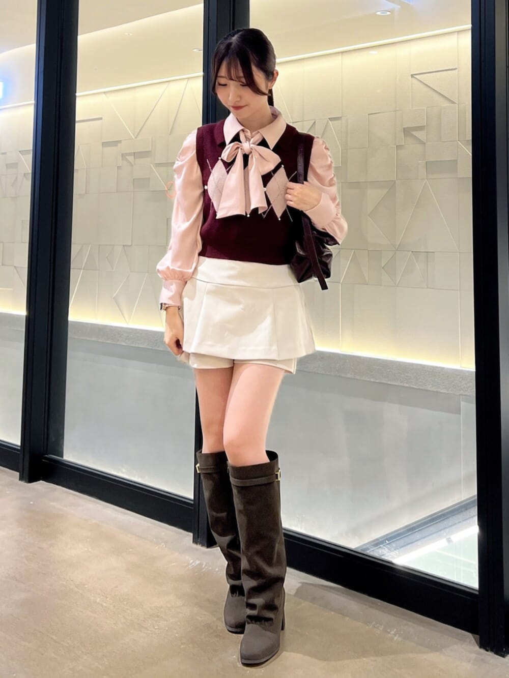 ブラウン系のブーツ、レッド系のハンドバッグ、ホワイト系のスカートを着用したレディースの秋コーディネートの4枚目の写真