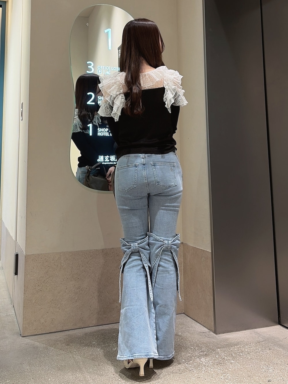 ブラック系のTシャツ/カットソー、ブルー系のデニムパンツ、ブラウン系のハンドバッグを着用したレディースの冬コーディネートの3枚目の写真