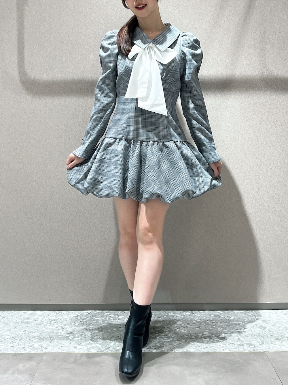 グレー系のワンピース、ブラック系のブーツを着用したレディースの秋コーディネートの4枚目の写真