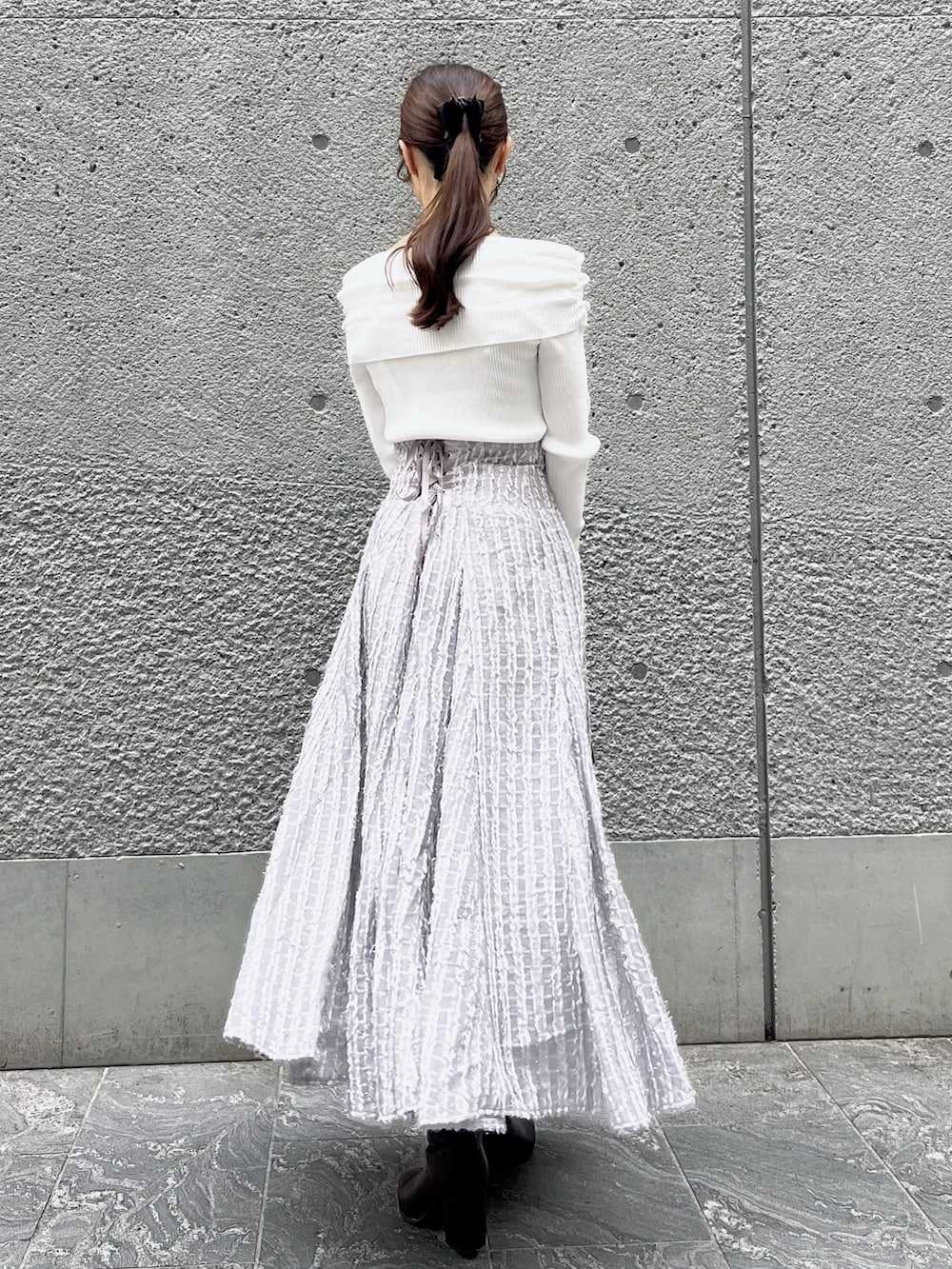 グレー系のスカート、ホワイト系のニット/セーター、ベージュ系のショルダーバッグを着用したレディースの秋コーディネートの4枚目の写真
