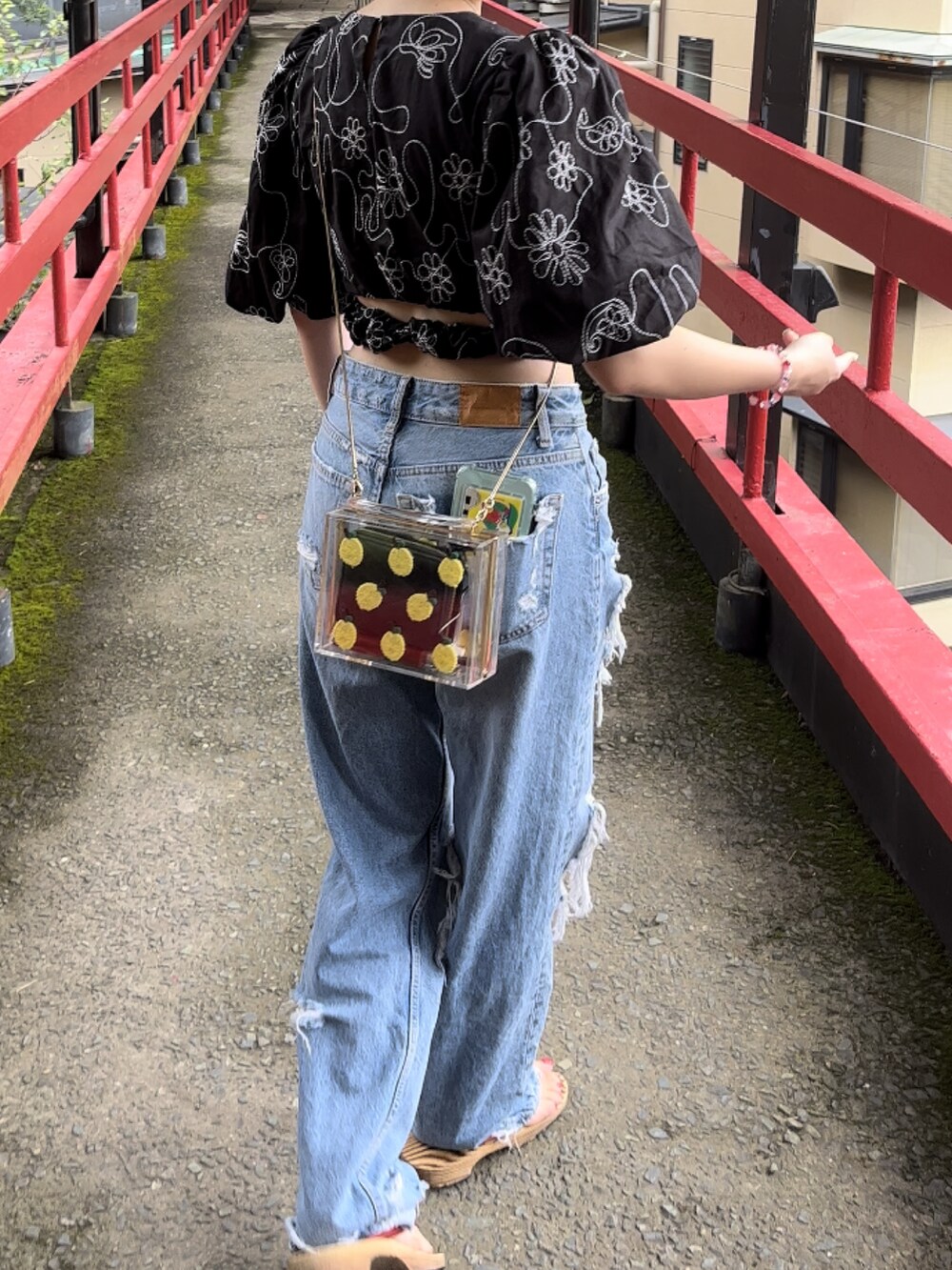 ブルー系のデニムパンツ、ブラック系のトップス、イエロー系のバッグを着用したレディースの秋コーディネートの3枚目の写真