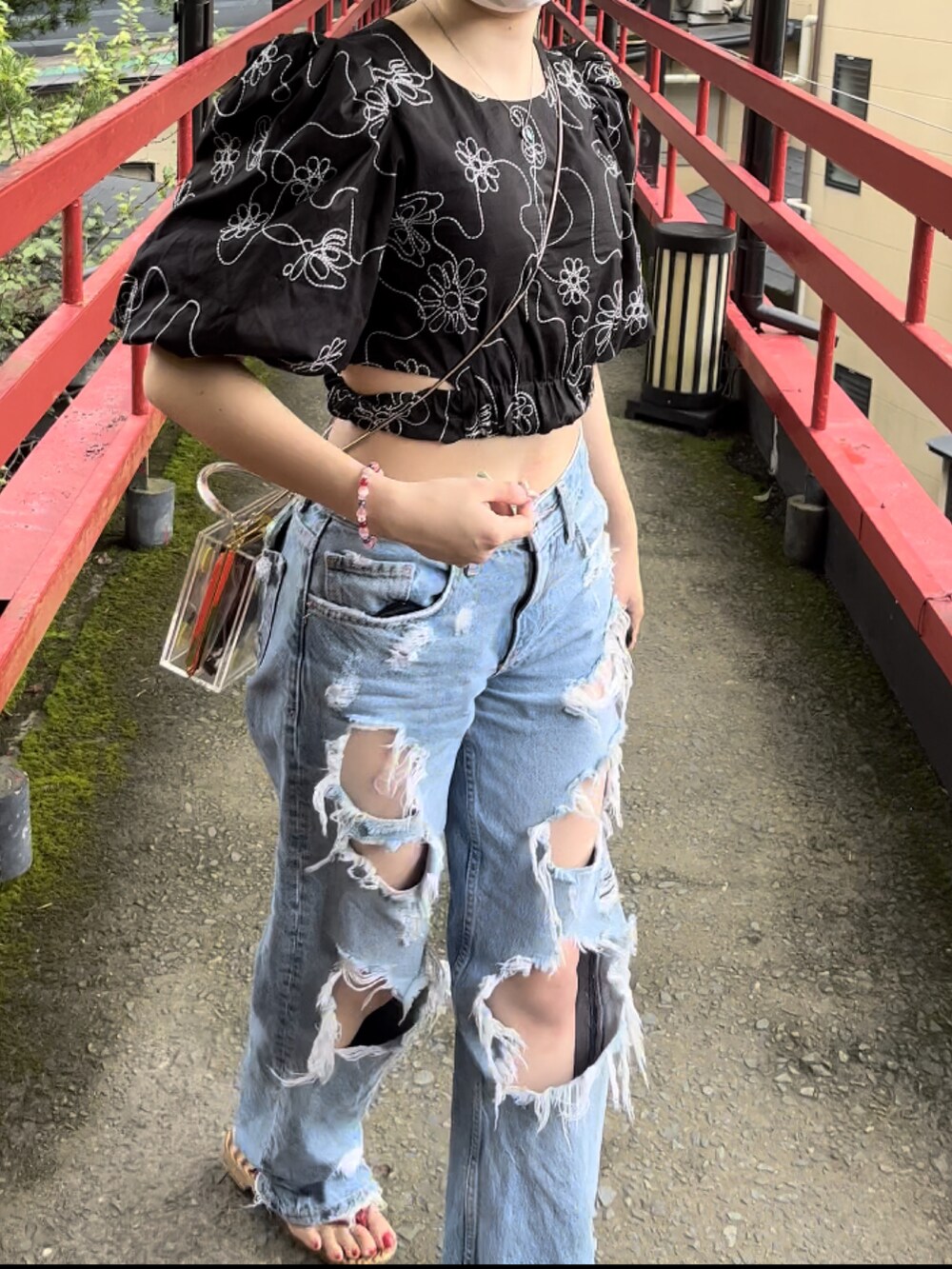 ブルー系のデニムパンツ、ブラック系のトップス、イエロー系のバッグを着用したレディースの秋コーディネートの2枚目の写真