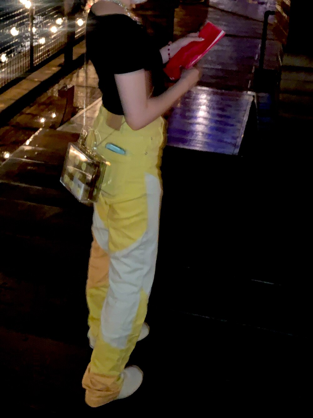 ブラック系のトップス、イエロー系のパンツ、ホワイト系のブーツを着用したレディースの秋コーディネートの2枚目の写真