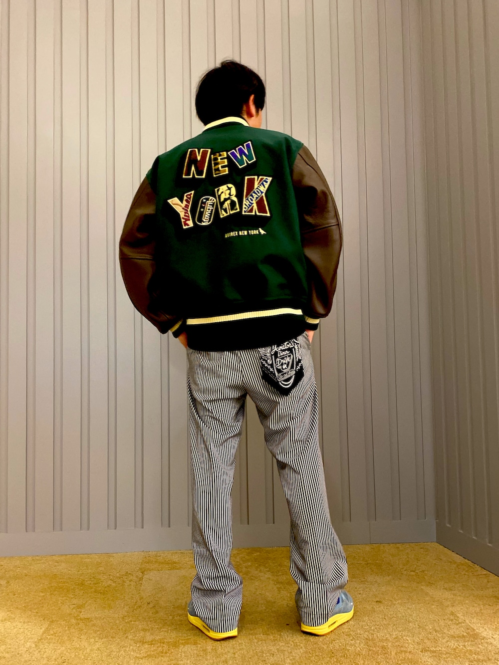 その他のチノパンツ、グリーン系のスタジャン、ブラック系のTシャツ/カットソーを着用したメンズの夏コーディネートの2枚目の写真