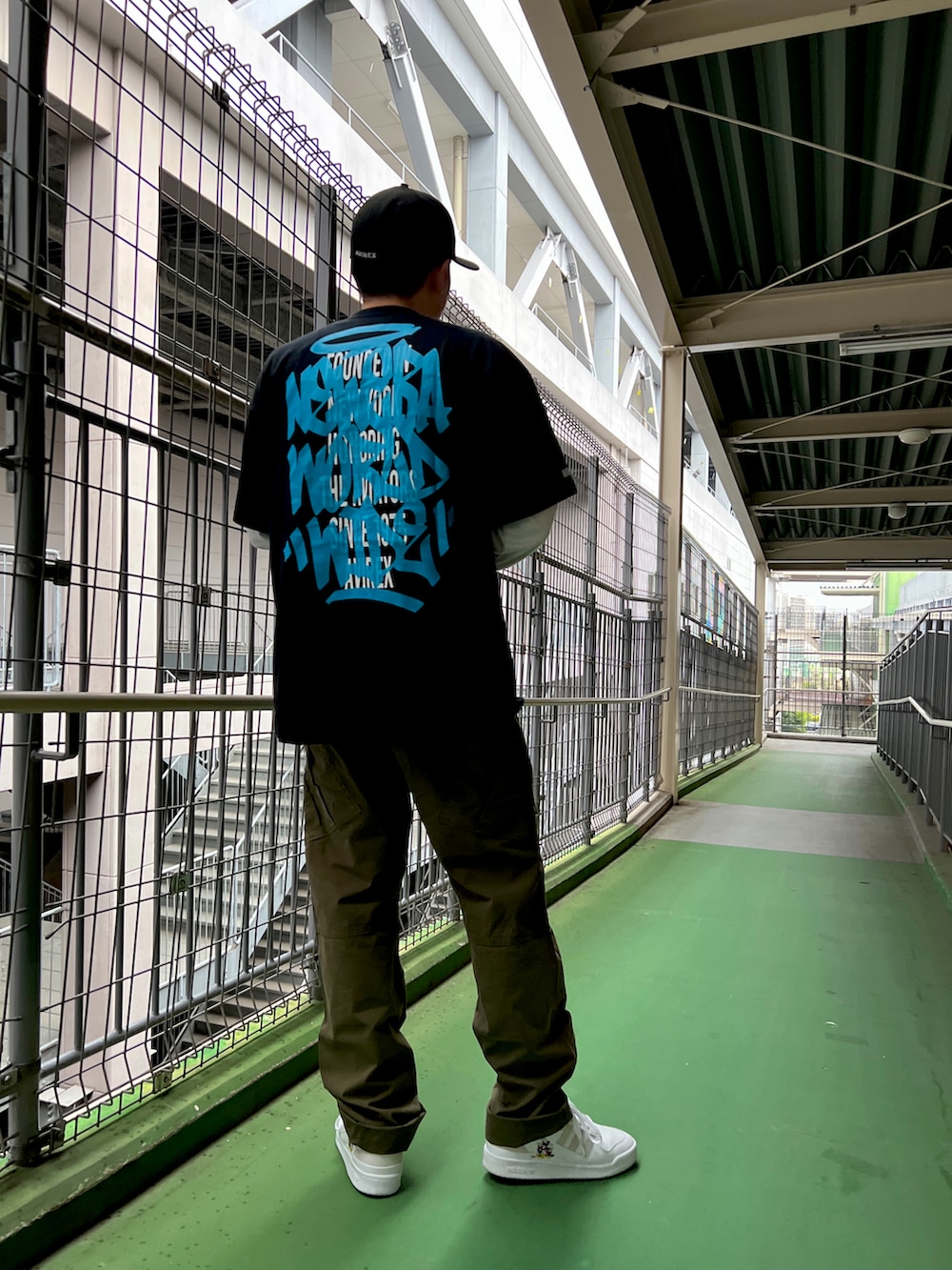 グリーン系のカーゴパンツ、ブラック系のTシャツ/カットソー、ブラック系のキャップを着用したメンズの春コーディネートの2枚目の写真