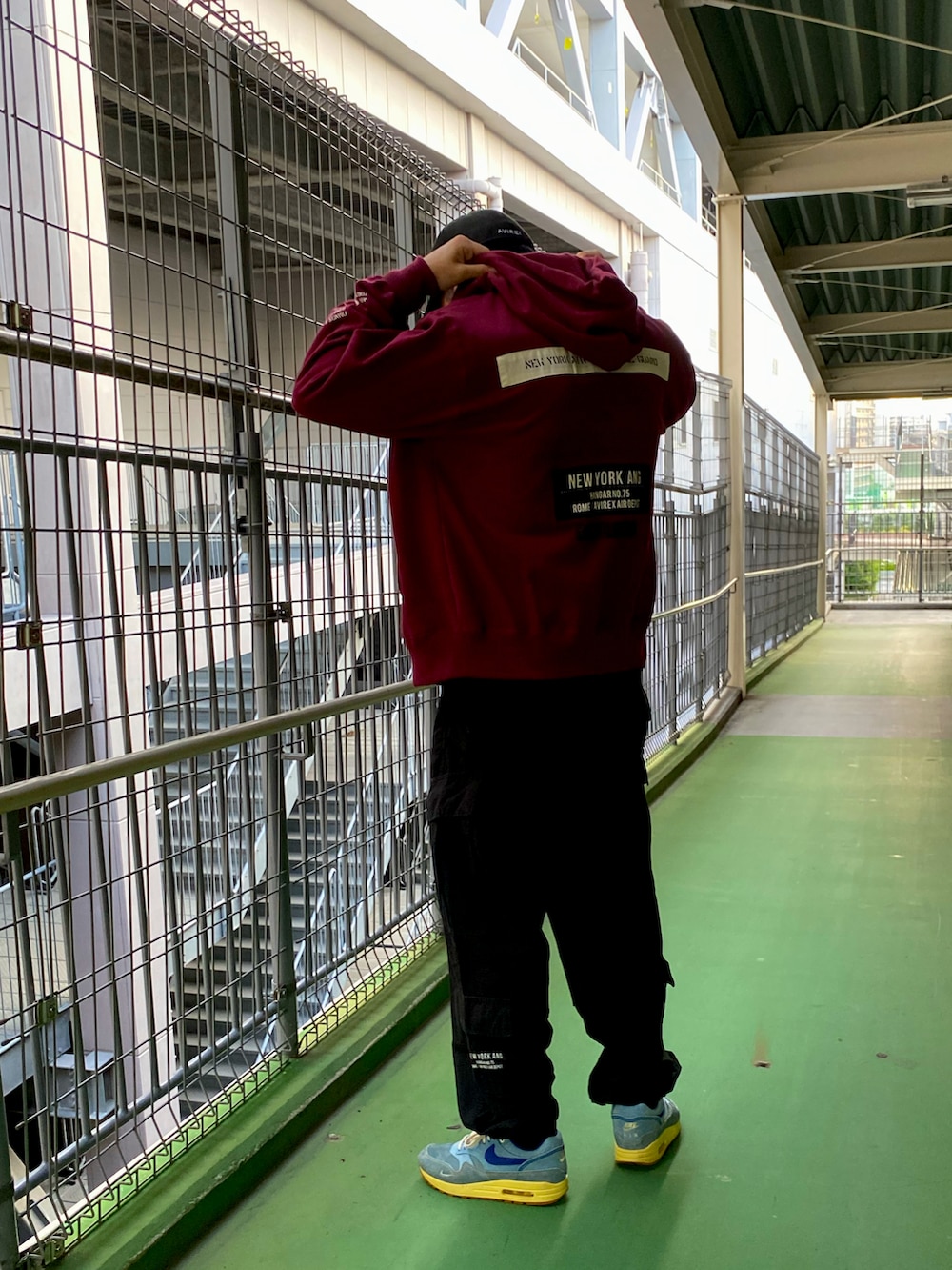 レッド系のパーカー、ブラック系のカーゴパンツ、ブラック系のTシャツ/カットソーを着用したメンズの夏コーディネートの2枚目の写真