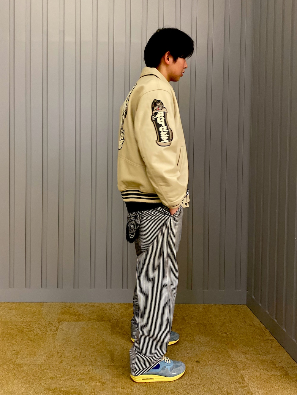 その他のチノパンツ、ホワイト系のスタジャン、ブラック系のTシャツ/カットソーを着用したメンズの夏コーディネートの2枚目の写真