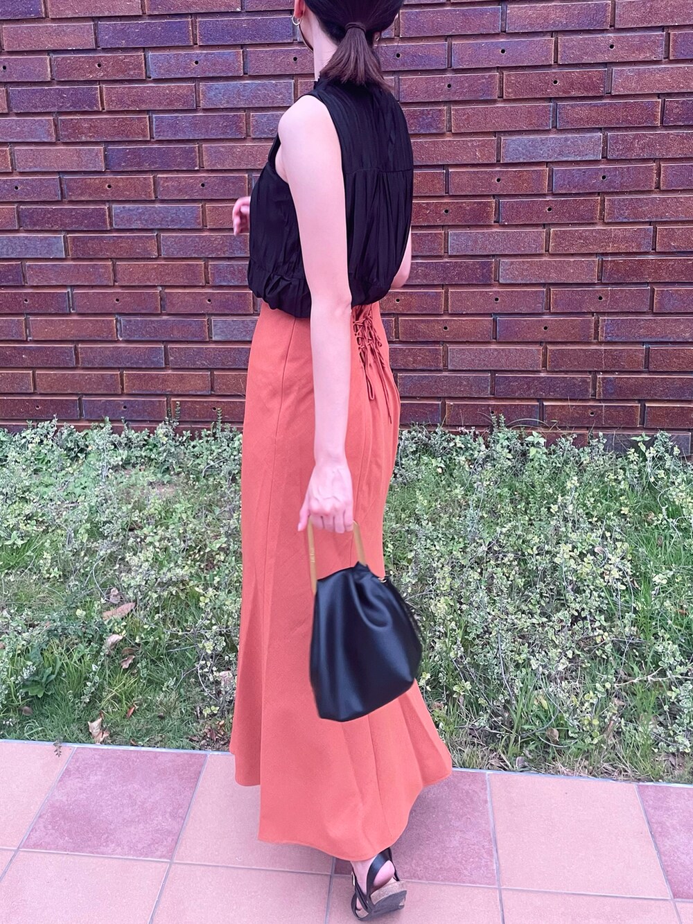 ブラック系のシャツ/ブラウス、オレンジ系のスカート、ブラック系のハンドバッグを着用したレディースの秋コーディネートの2枚目の写真