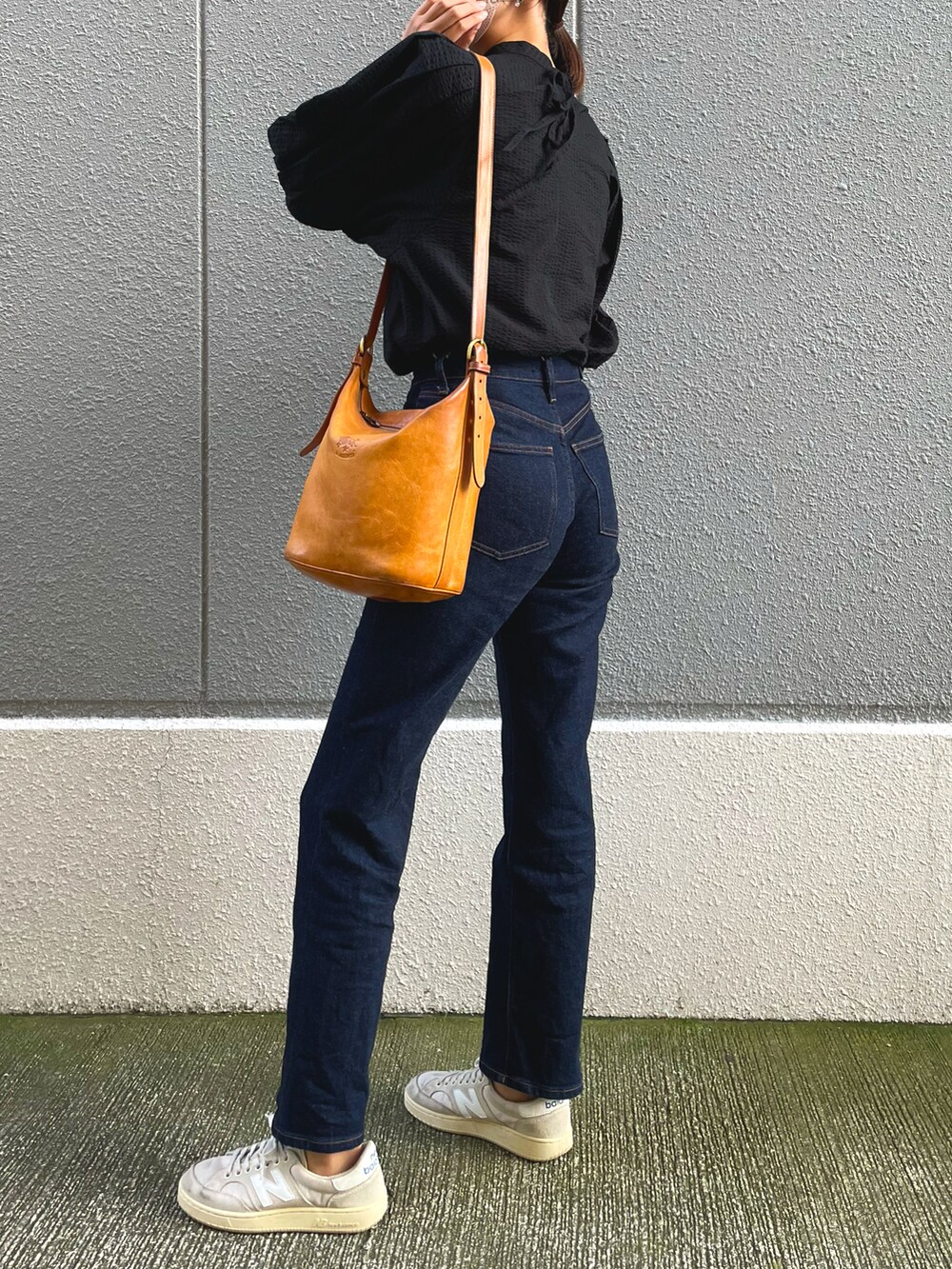 ブラック系のシャツ/ブラウス、オレンジ系のショルダーバッグ、グレー系のデニムパンツを着用したレディースの秋コーディネートの2枚目の写真