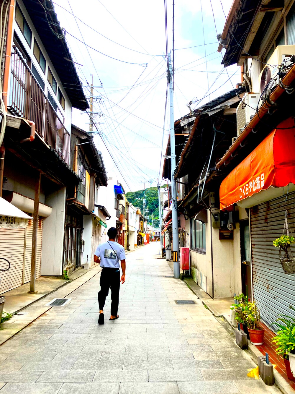 ブラック系のスラックス、ブラウン系のサンダル、グレー系のTシャツ/カットソーを着用したメンズの夏コーディネートの2枚目の写真
