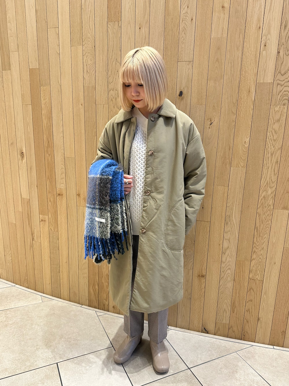 グリーン系のステンカラーコート、ホワイト系のニット/セーター、ベージュ系のその他パンツを着用したレディースの秋コーディネートの3枚目の写真