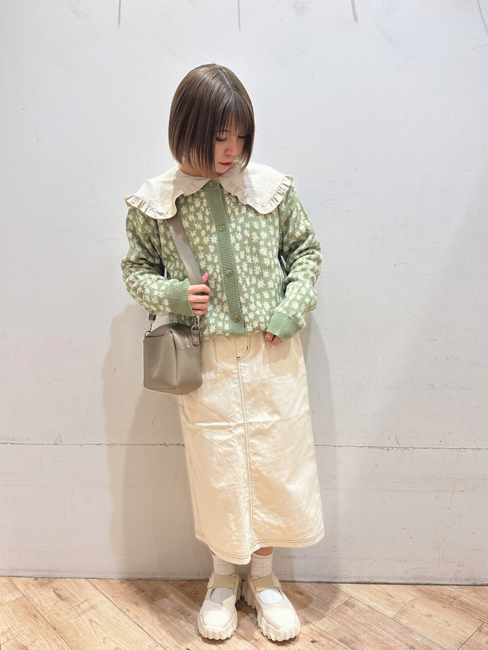 グリーン系のカーディガン/ボレロ、ベージュ系のシャツ/ブラウス、ホワイト系のスカートを着用したレディースの冬コーディネートの2枚目の写真
