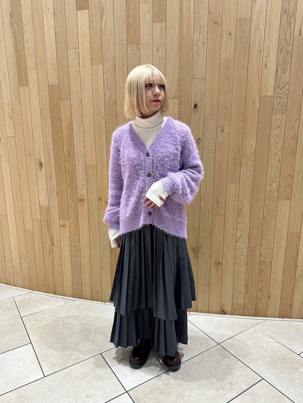 パープル系のカーディガン/ボレロ、ホワイト系のTシャツ/カットソー、グレー系のスカートを着用したレディースの秋コーディネートの2枚目の写真