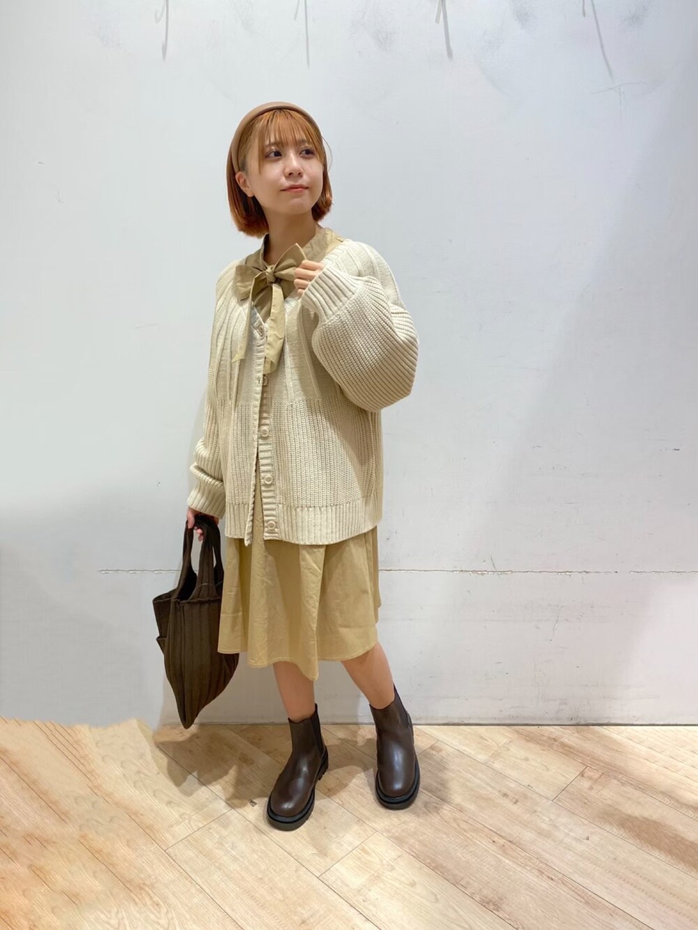 ベージュ系のカーディガン/ボレロ、ベージュ系のワンピース、ブラウン系のブーツを着用したレディースの秋コーディネートの2枚目の写真