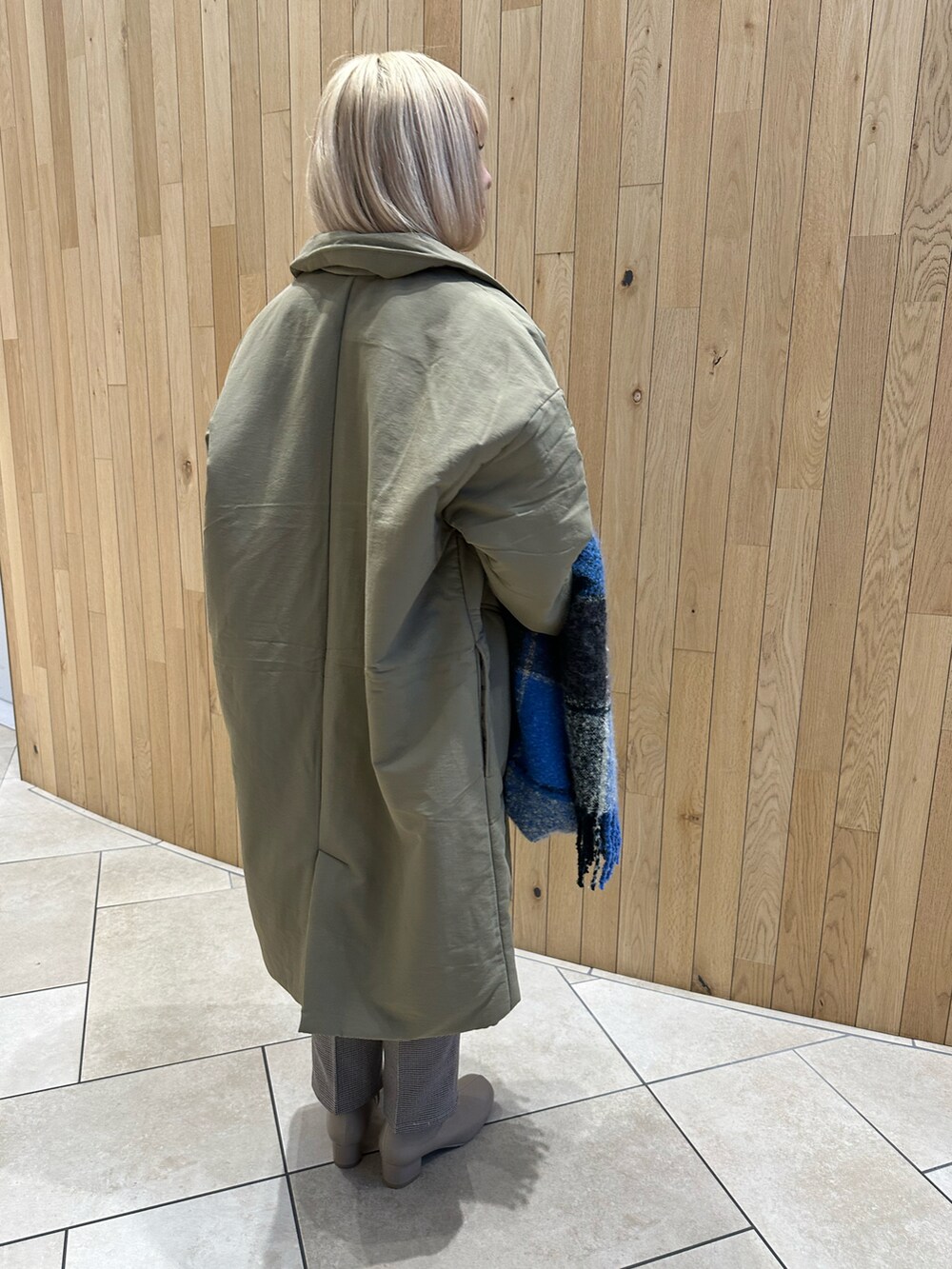 グリーン系のステンカラーコート、ホワイト系のニット/セーター、ベージュ系のその他パンツを着用したレディースの秋コーディネートの4枚目の写真