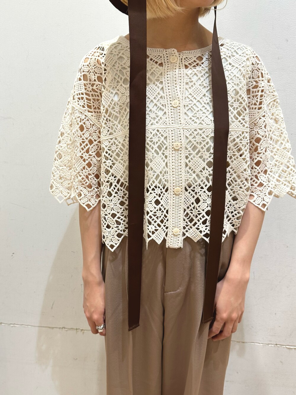 ホワイト系のタンクトップ、ベージュ系のトップス、ブラウン系のその他パンツを着用したレディースの春コーディネートの4枚目の写真