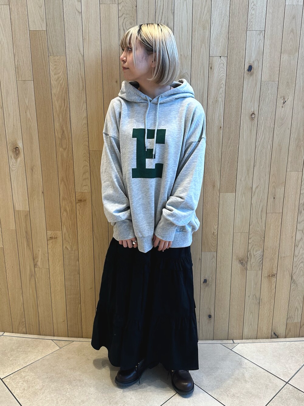 グレー系のTシャツ/カットソー、ブラック系のスカート、ブラウン系のブーツを着用したレディースの冬コーディネートの2枚目の写真