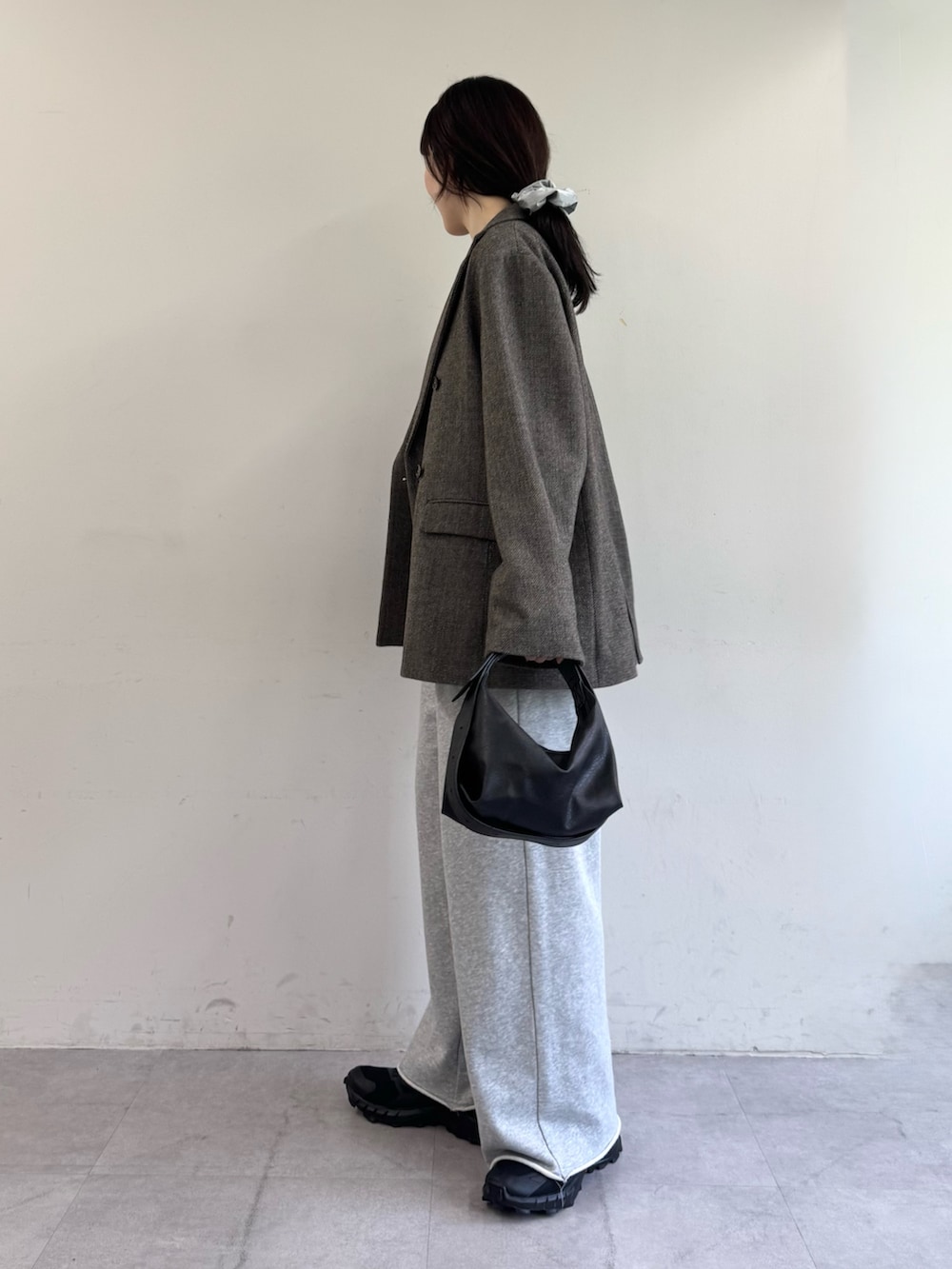 ブラウン系のテーラードジャケット、グレー系のスウェットパンツ、ブラック系のショルダーバッグを着用したレディースの夏コーディネートの2枚目の写真