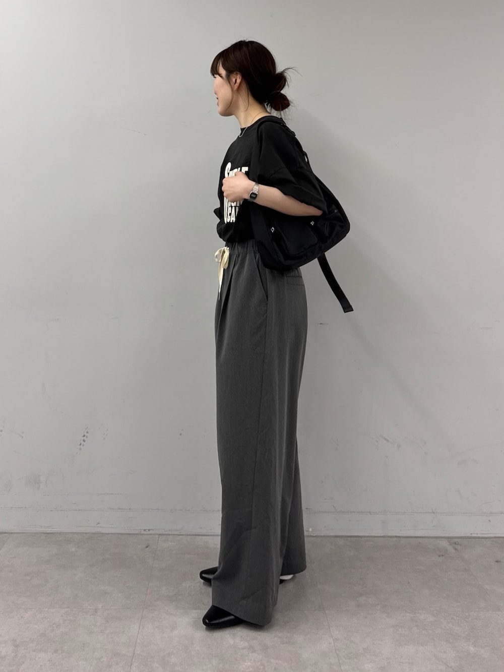 ブラック系のTシャツ/カットソー、ブラック系のショルダーバッグ、グレー系のデニムパンツを着用したレディースの春コーディネートの2枚目の写真