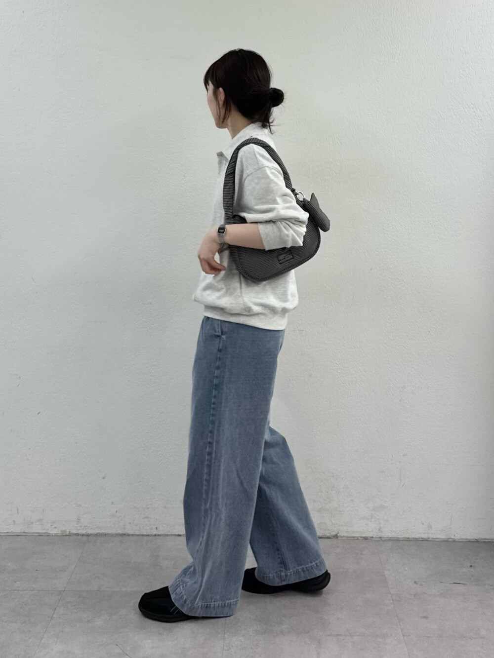 グレー系のスウェット、ブラック系のショルダーバッグ、ブルー系のデニムパンツを着用したレディースの春コーディネートの2枚目の写真
