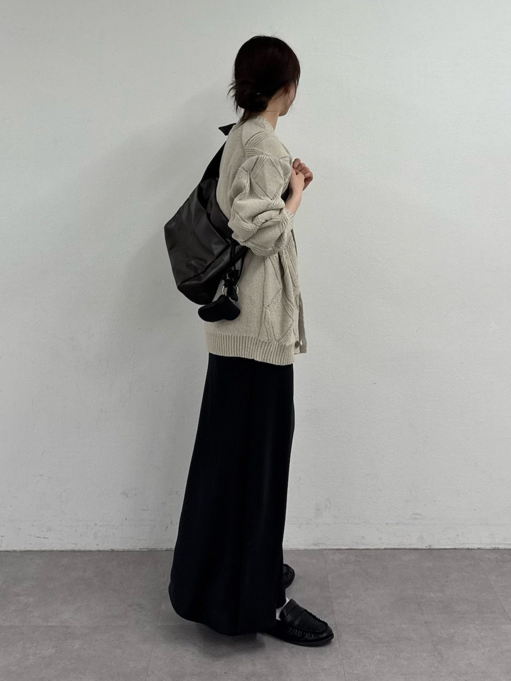 ベージュ系のカーディガン/ボレロ、ブラック系のスカートを着用したレディースの春コーディネートの2枚目の写真