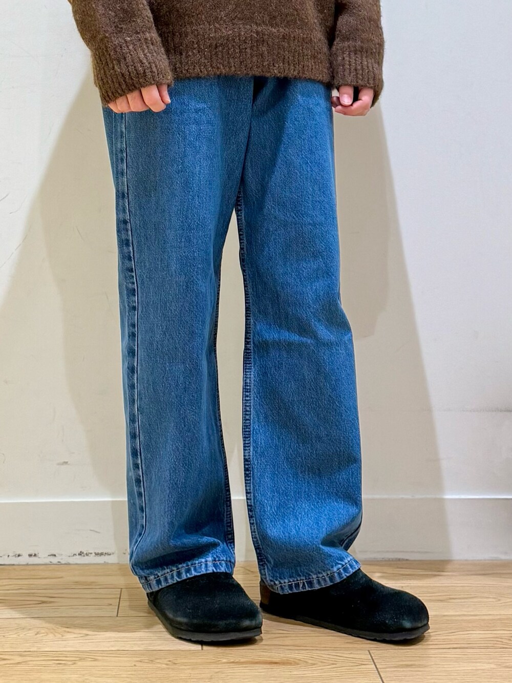 ブラウン系のニット/セーター、ブルー系のデニムパンツ、ブラック系のサンダルを着用したメンズの秋コーディネートの7枚目の写真