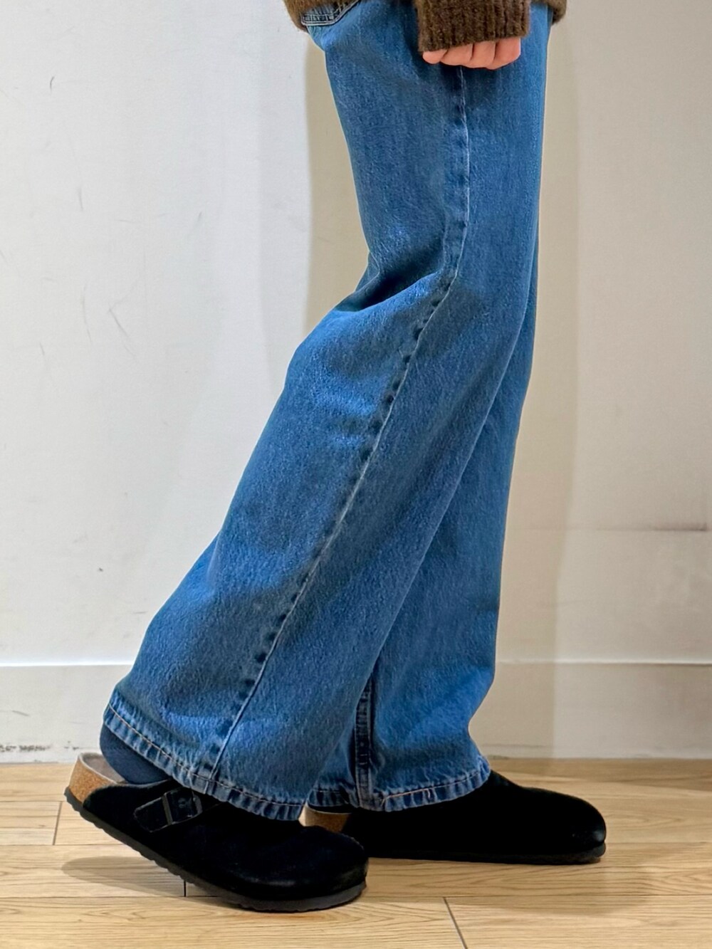 ブラウン系のニット/セーター、ブルー系のデニムパンツ、ブラック系のサンダルを着用したメンズの秋コーディネートの8枚目の写真