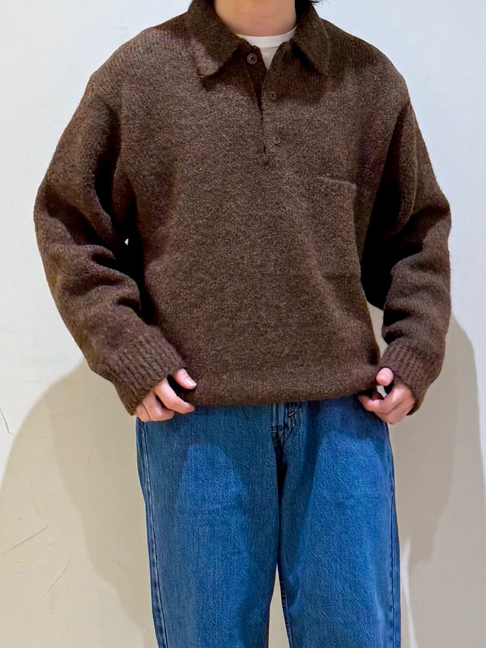 ブラウン系のニット/セーター、ブルー系のデニムパンツ、ブラック系のサンダルを着用したメンズの秋コーディネートの5枚目の写真