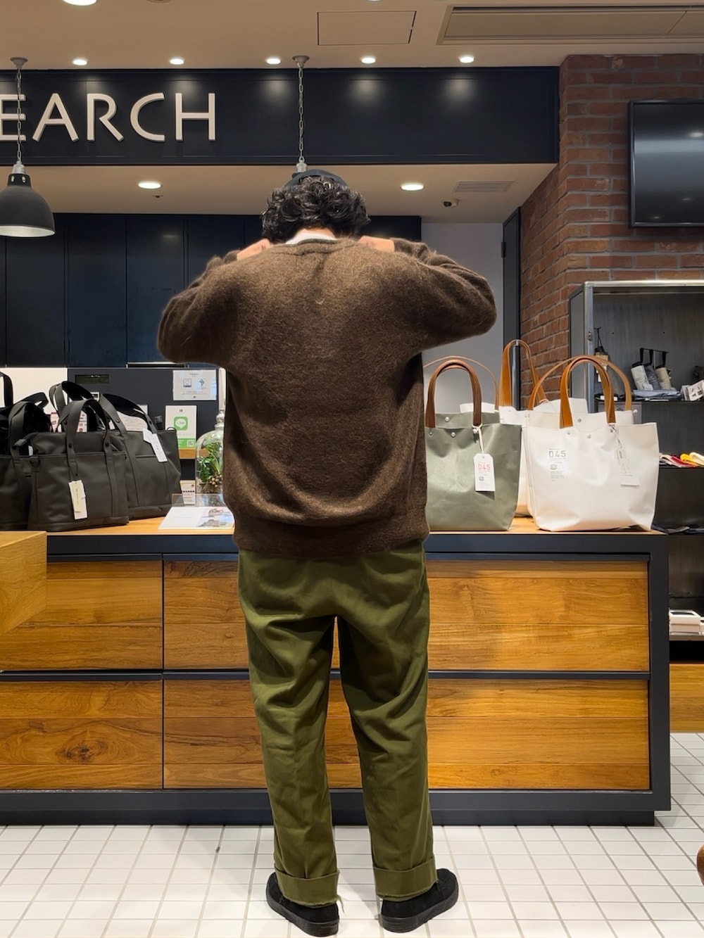 ブラウン系のカーディガン/ボレロ、ブラック系のローファー、ブルー系のキャップを着用したメンズの秋コーディネートの3枚目の写真