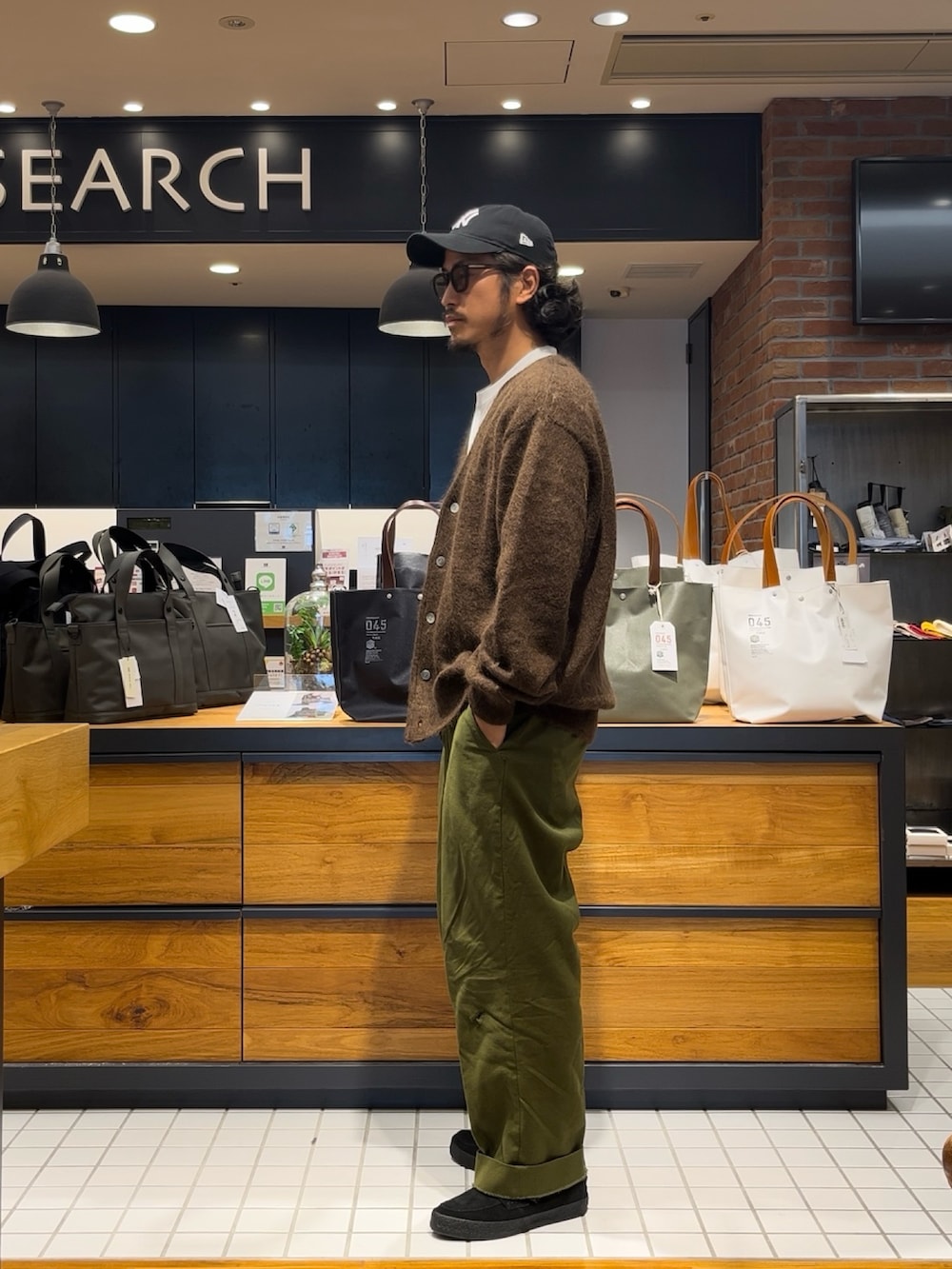 ブラウン系のカーディガン/ボレロ、ブラック系のローファー、ブルー系のキャップを着用したメンズの秋コーディネートの4枚目の写真