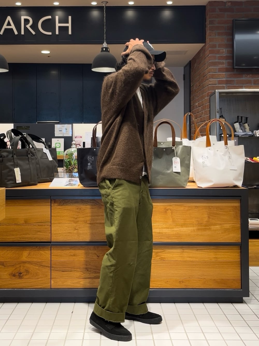 ブラウン系のカーディガン/ボレロ、ブラック系のローファー、ブルー系のキャップを着用したメンズの秋コーディネートの2枚目の写真