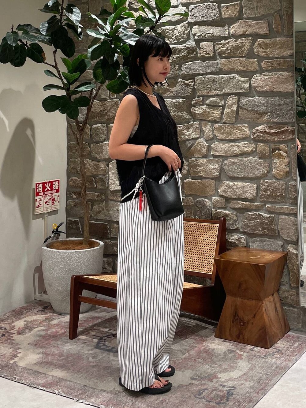 ブラック系のベスト、ブラック系のハンドバッグ、ホワイト系のその他パンツを着用したレディースの夏コーディネートの5枚目の写真