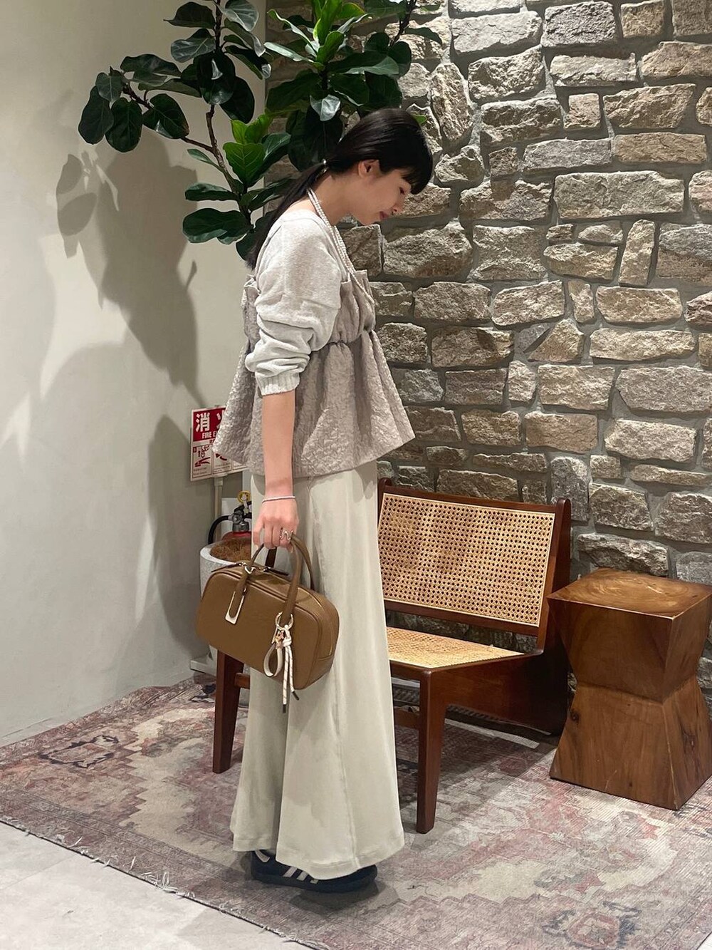 イエロー系のショルダーバッグ、ホワイト系のニット/セーター、ベージュ系のキャミソールを着用したレディースの春コーディネートの3枚目の写真