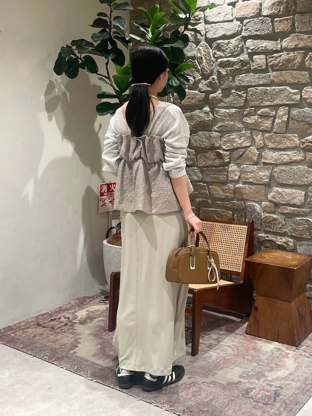 イエロー系のショルダーバッグ、ホワイト系のニット/セーター、ベージュ系のキャミソールを着用したレディースの春コーディネートの4枚目の写真