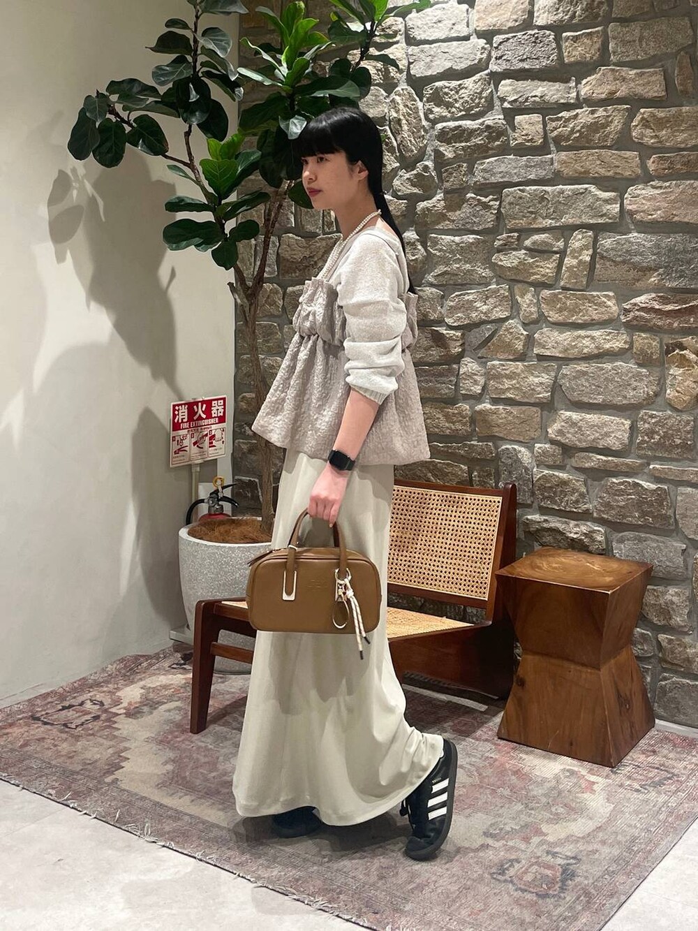 イエロー系のショルダーバッグ、ホワイト系のニット/セーター、ベージュ系のキャミソールを着用したレディースの春コーディネートの2枚目の写真