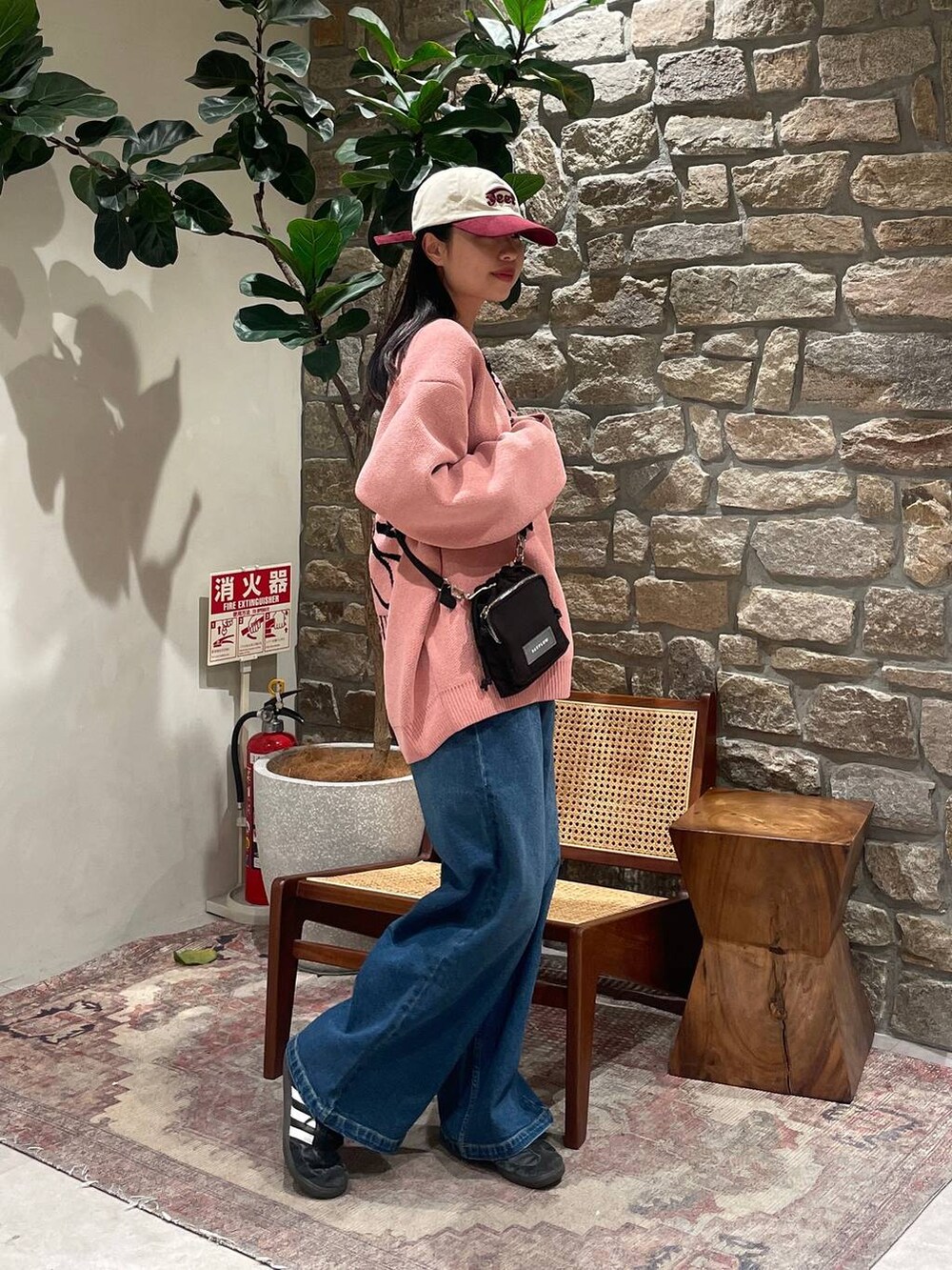 ピンク系のニット/セーター、ブラック系のショルダーバッグ、ブルー系のデニムパンツを着用したレディースの冬コーディネートの2枚目の写真