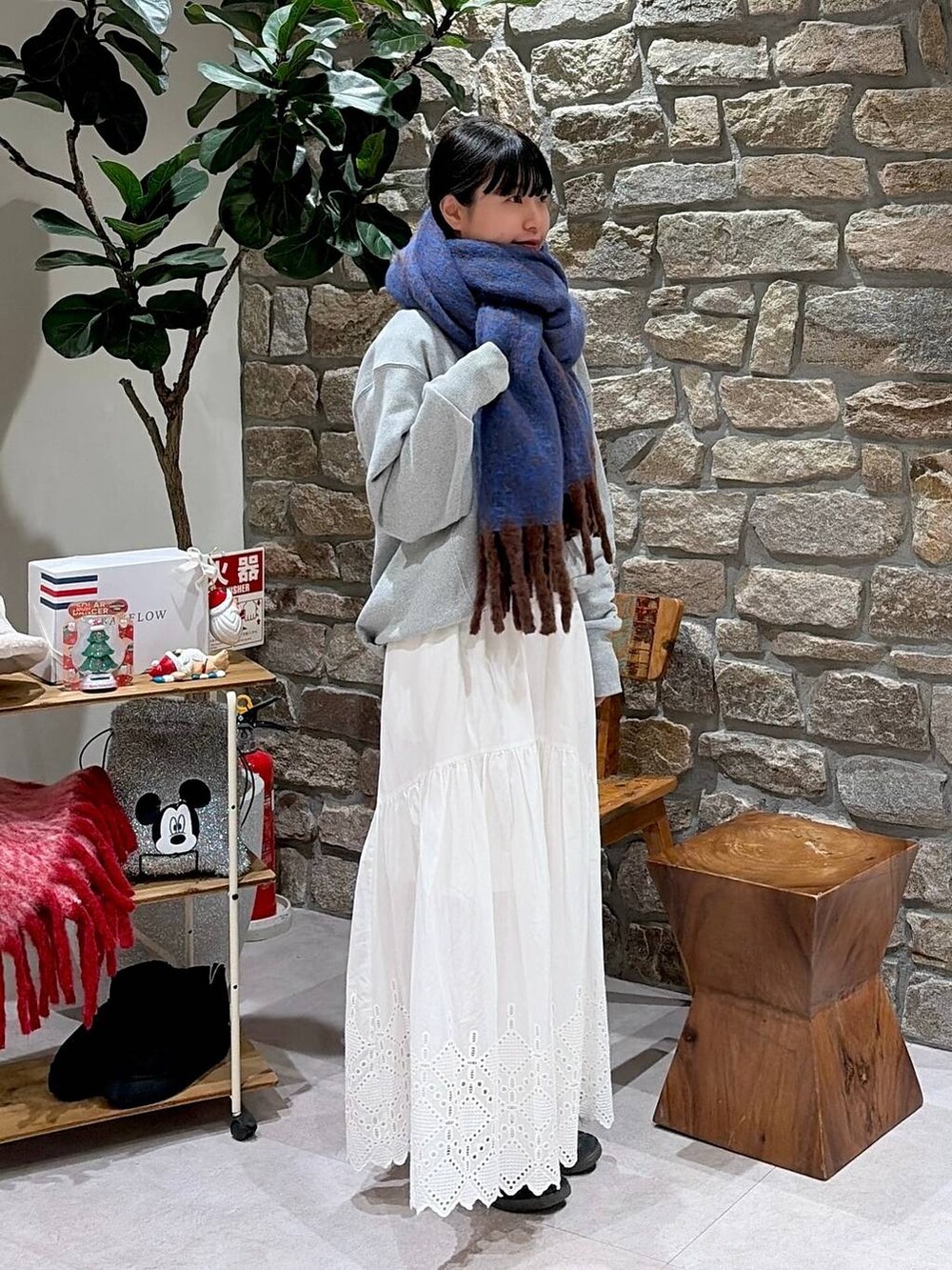 グレー系のスウェット、ホワイト系のスカート、ブルー系のマフラーを着用したレディースの秋コーディネートの2枚目の写真