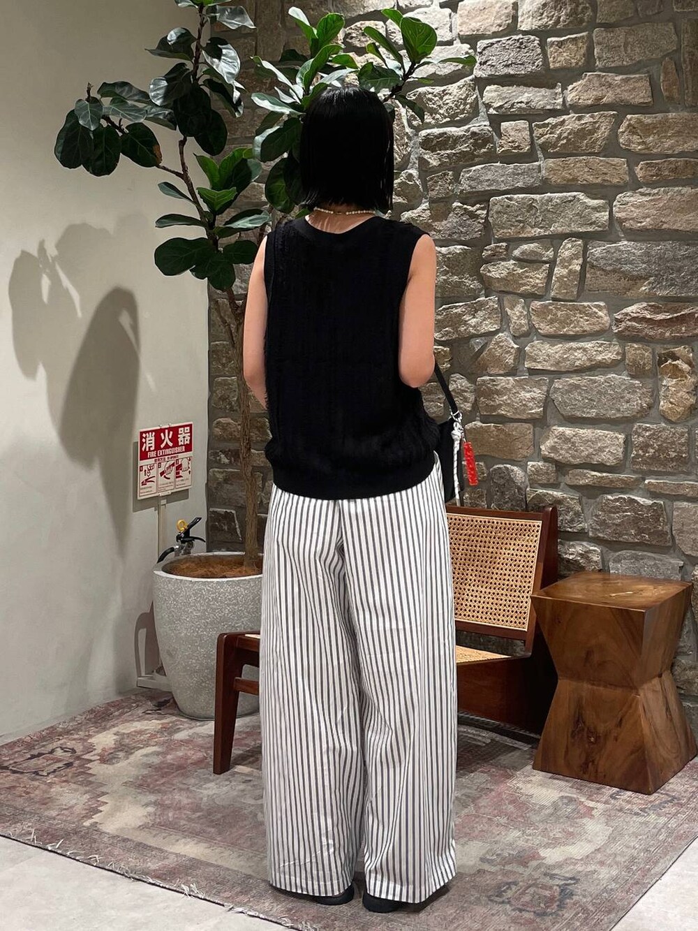 ブラック系のベスト、ブラック系のハンドバッグ、ホワイト系のその他パンツを着用したレディースの夏コーディネートの6枚目の写真