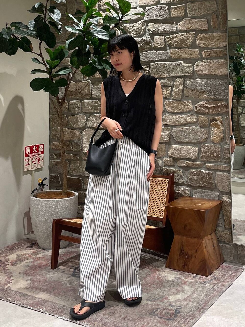 ブラック系のベスト、ブラック系のハンドバッグ、ホワイト系のその他パンツを着用したレディースの夏コーディネートの4枚目の写真