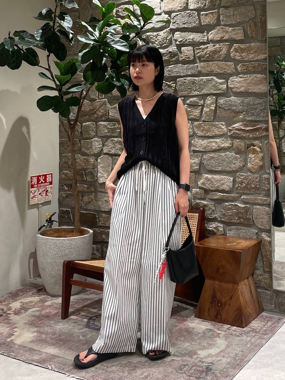 ブラック系のベスト、ブラック系のハンドバッグ、ホワイト系のその他パンツを着用したレディースの夏コーディネートの3枚目の写真