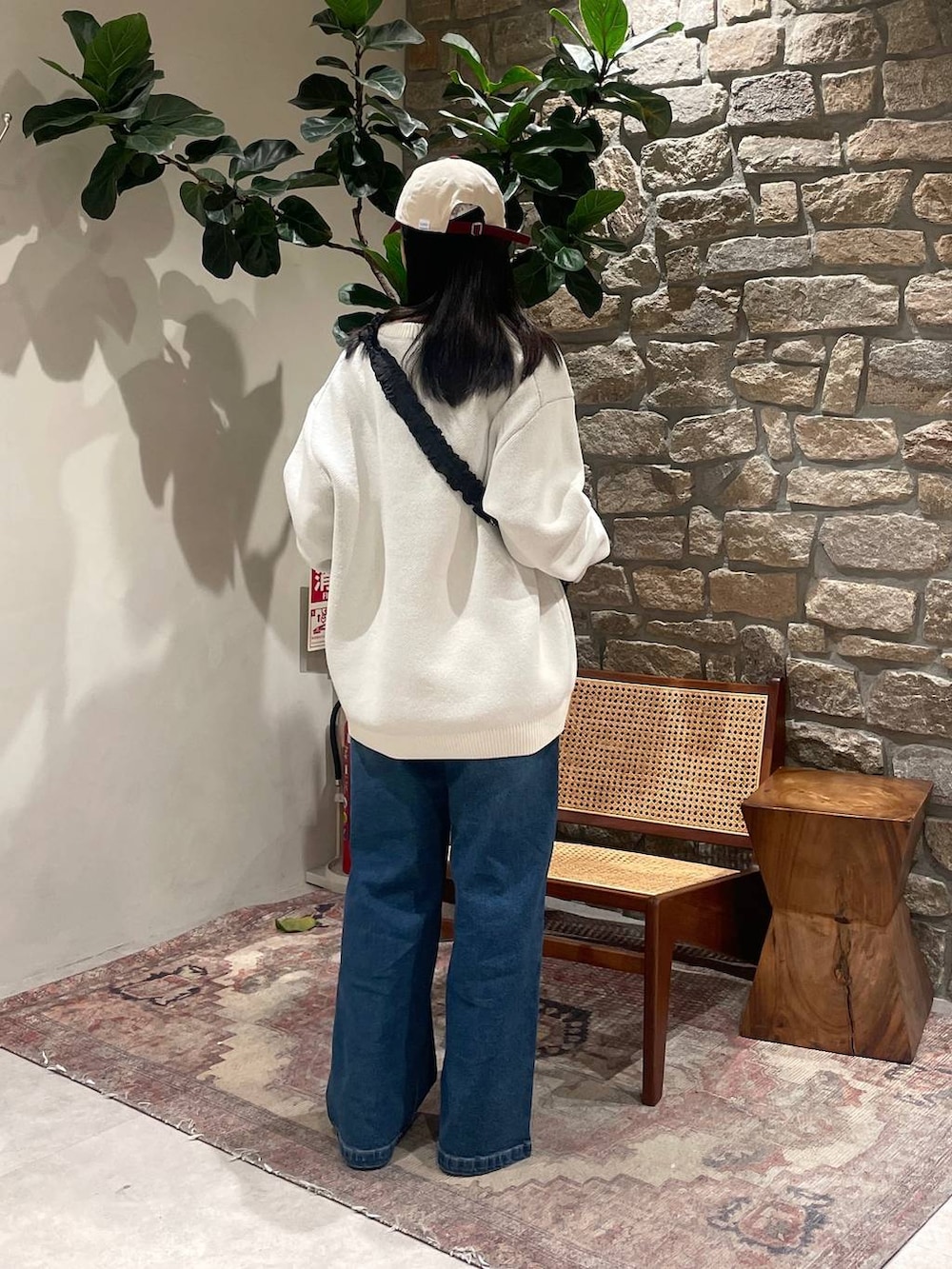 ホワイト系のニット/セーター、ブラック系のショルダーバッグ、ブルー系のデニムパンツを着用したレディースの冬コーディネートの5枚目の写真