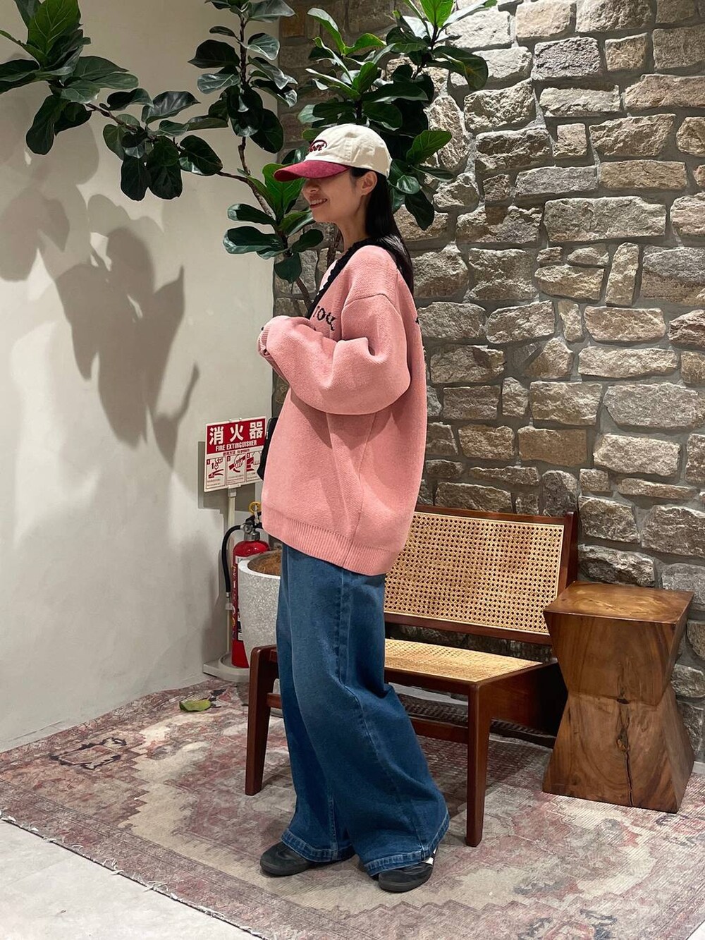 ピンク系のニット/セーター、ブラック系のショルダーバッグ、ブルー系のデニムパンツを着用したレディースの冬コーディネートの3枚目の写真